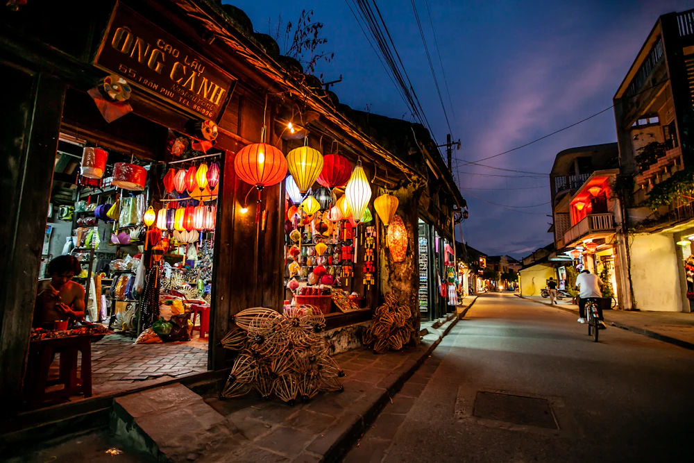 A cyclist on a lantern-lit street in Hoi An's old town at night