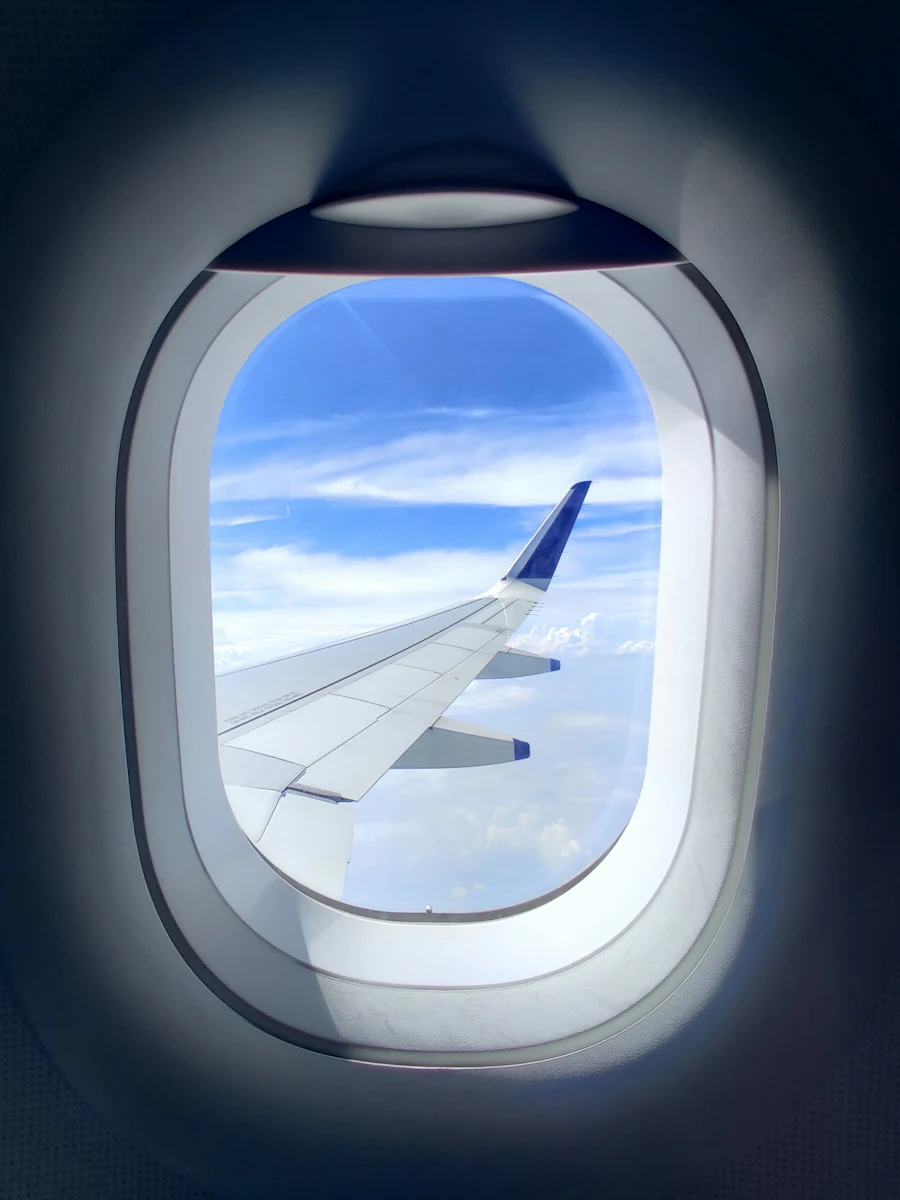A wing and blue sky seen through an airplane window